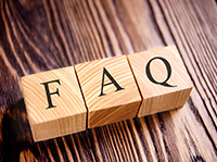 Three wooden FAQ letter blocks on wooden table