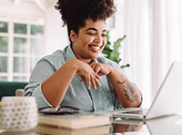 Woman smiling while working on laptop at home