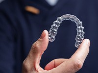 Man in navy scrubs holding Invisalign tray