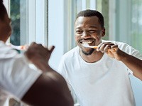 Man smiling while brushing his teeth