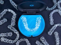 Bird’s eye view of several Invisalign trays around carrying case with black background