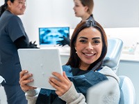 Woman smiling while holding mirror in treatment chair