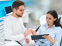 Man dressed in white handing patient forms on clipboard to fill out