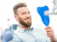 bearded man admiring his own smile after getting dental implants 