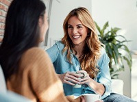 Woman smiling while drinking coffee with friend