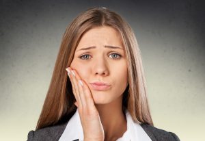 Woman with lost dental filling with hand to face