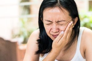 Woman with hand on her face from pain