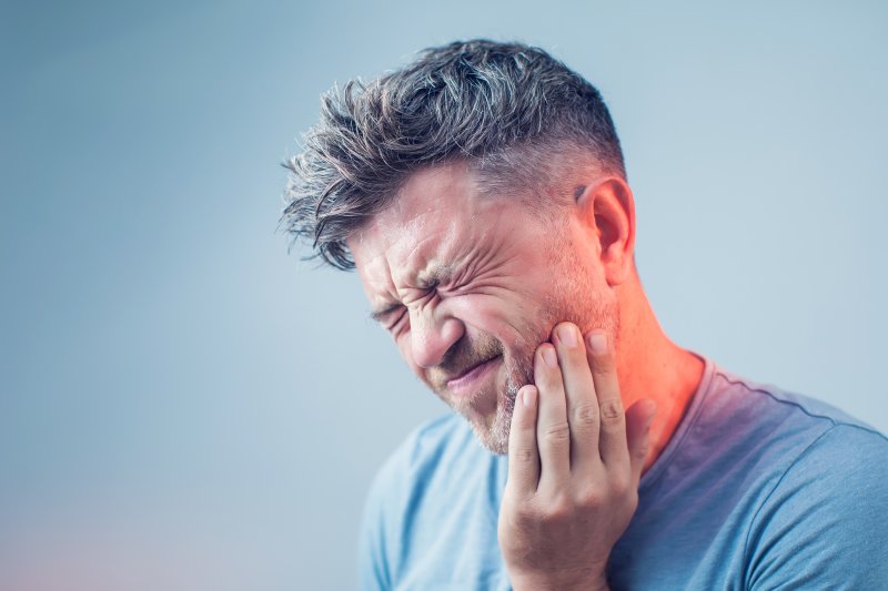 person with jaw pain holding their cheek