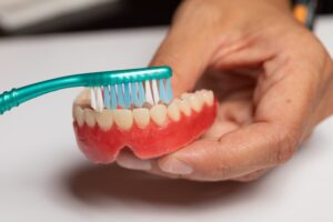 Person brushing their dentures to get rid of a bad smell