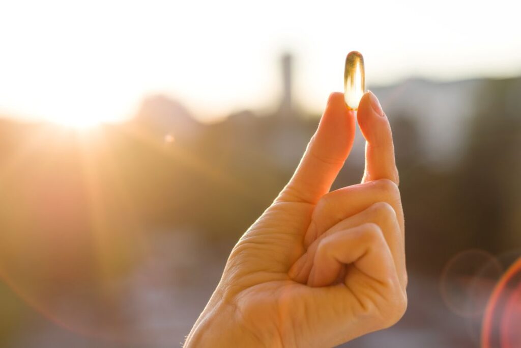 A hand holding a vitamin D gelcap
