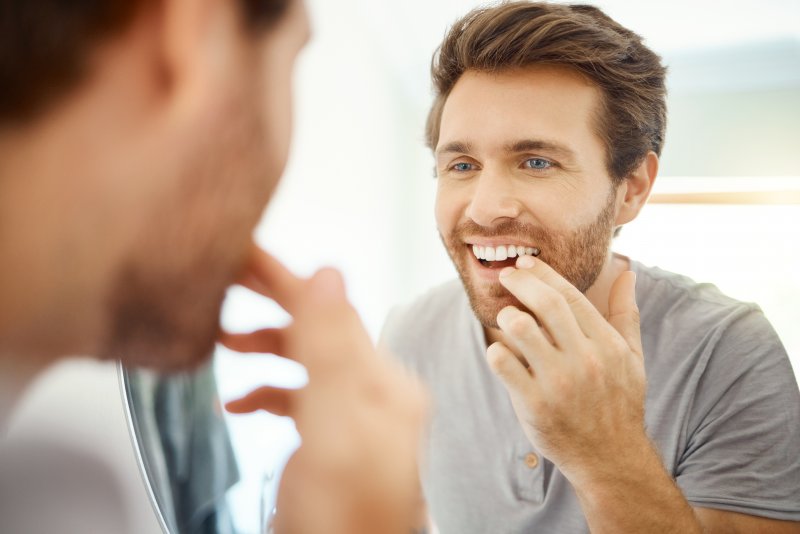 Patient smiling in mirror after getting veneers
